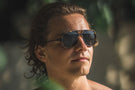 Tortoise_grey Long haired man wearing Ombraz tortoise grey classic armless sunglasses with cord