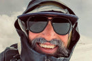 MATTEBROWN_GREY Man with snow on his moustache wearing Ombraz classic armless string sunglasses under a hoodie and hat