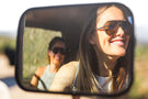 MATTEBROWN_yellow Two women smiling in a rear view mirror wearing Ombraz classic armless string sunglasses