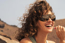 black_ice_silver_mirror Woman smiling and drinking wearing Ombraz viale tortoise brown sunglasses with shields