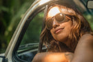 MATTEBROWN_BROWN Woman looking out of the window of her car wearing Ombraz classic armless rope sunglasses