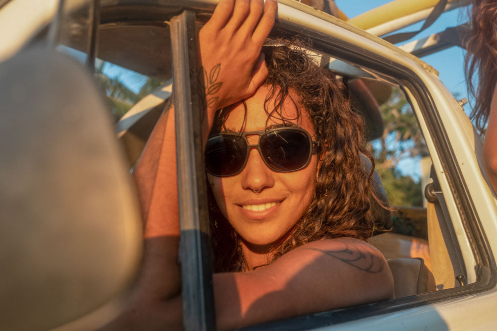 leggero_charcoal_brown Woman in the sun sitting passenger seat in a car wearing Ombraz leggero armless sunglasses with cord