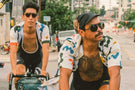 dolomite_tortoise_grey Two men biking in the city wearing Ombraz unisex armless sunglasses with string