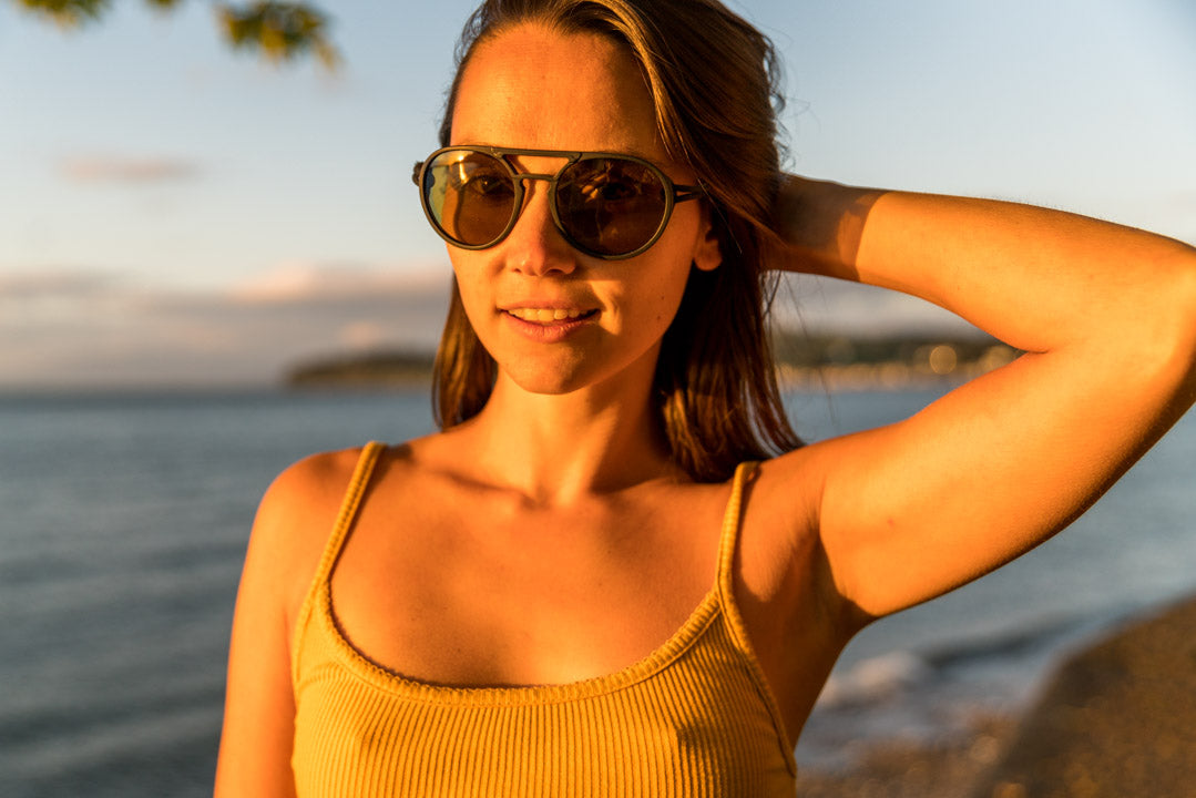 dolomite_tortoise_yellow Woman at the beach smiling wearing Ombraz unisex armless strap sunglasses