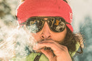 MATTEBROWN_GREY Man smoking a joint wearing Ombraz classic armless sunglasses with strap over a headband