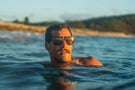 leggero_charcoal_yellow Man swimming wearing Ombraz leggero armless sunglasses with cord