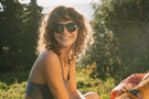 viale_dusk_grey Woman smiling outside wearing Ombraz viale dusk grey armless sunglasses with cord