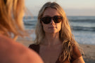 TETON_TORTOISE_BROWN Portrait of woman on the beach wearing Ombraz teton armless strap sunglasses