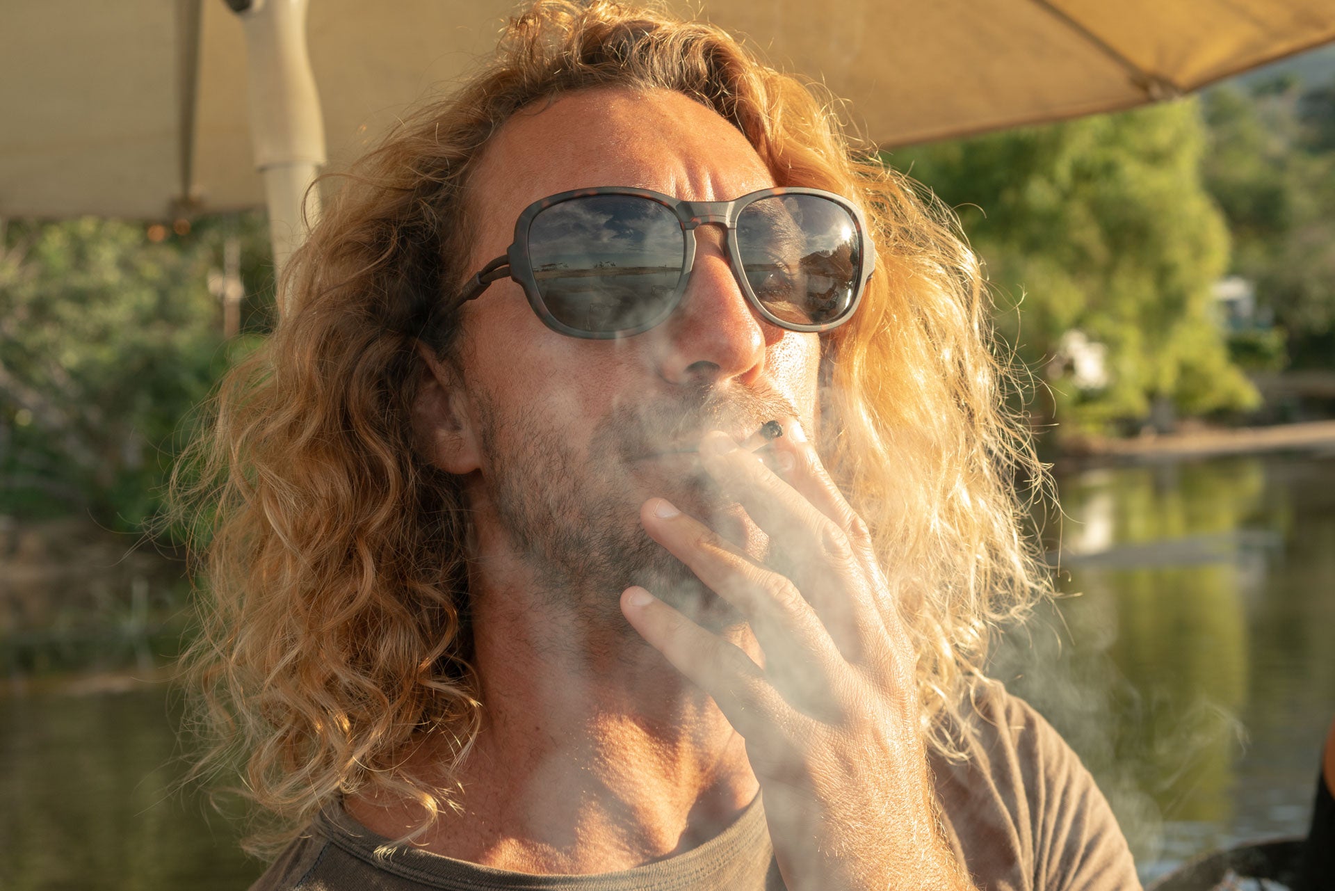 TETON_TORTOISE_GREY Portrait of man smoking wearing Ombraz armless strap sunglasses