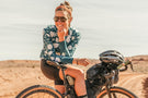 tortoise_brown Woman on her bike in the desert smiling wearing Ombraz tortoise brown classic armless sunglasses