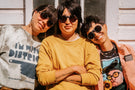 Portrait of three women posing in front of a house wearing Ombraz armless viale sunglasses with strap VIALE_CHARCOAL_BROWN