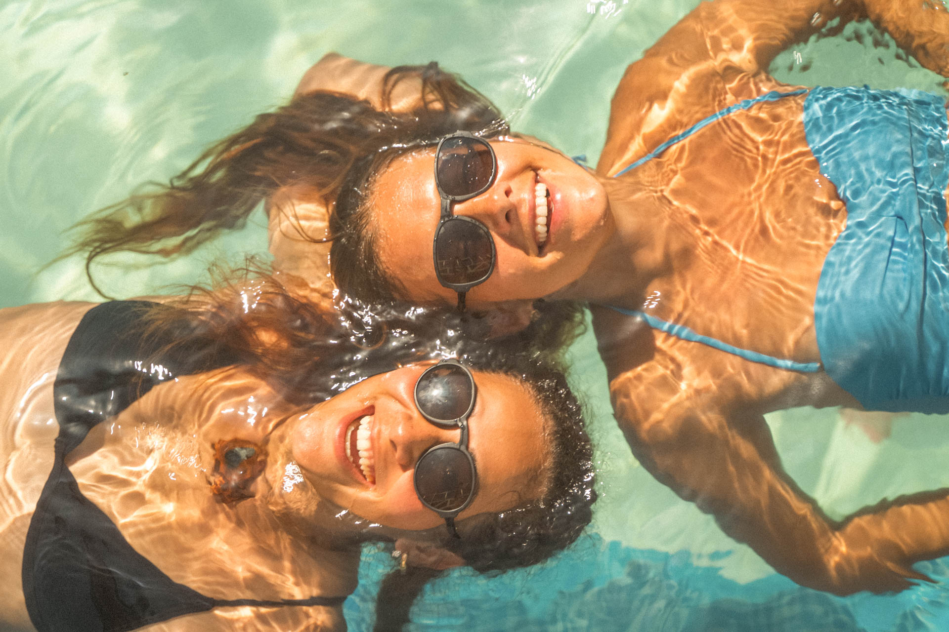 VIALE_CHARCOAL_GREY Two women swimming wearing Ombraz armless sunglasses